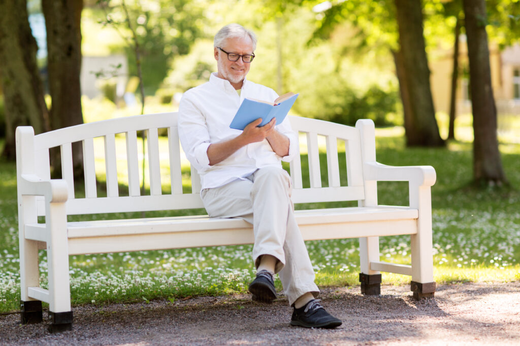 happy senior man reading book at summer park 2022 12 16 09 44 35 utc